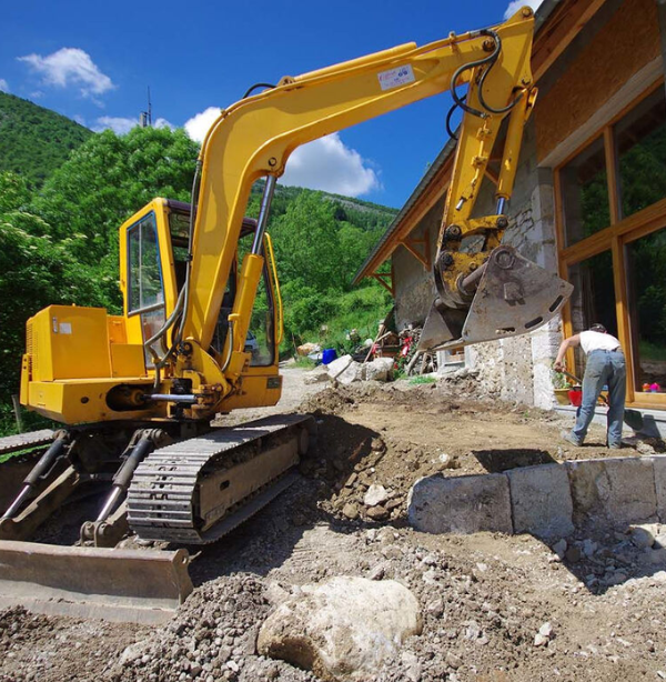 Grote graafmachine verricht grondwerken naast een gebouw. Voorbereiding voor bouw of asbestverwijdering.